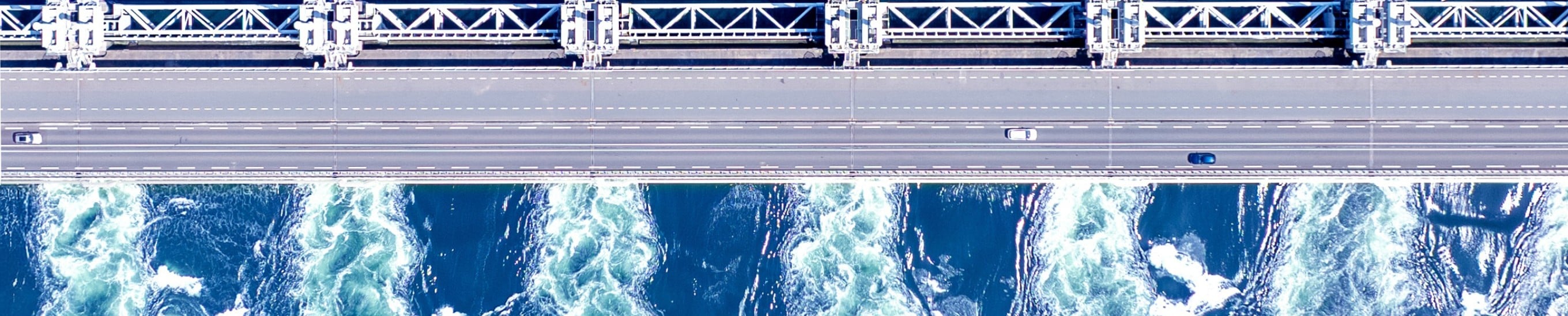 Aerial view of a highway bridge and storm surge barrier spanning open water, illustrating CBRE Investment Management's Macro House View Q3 2026 outlook.