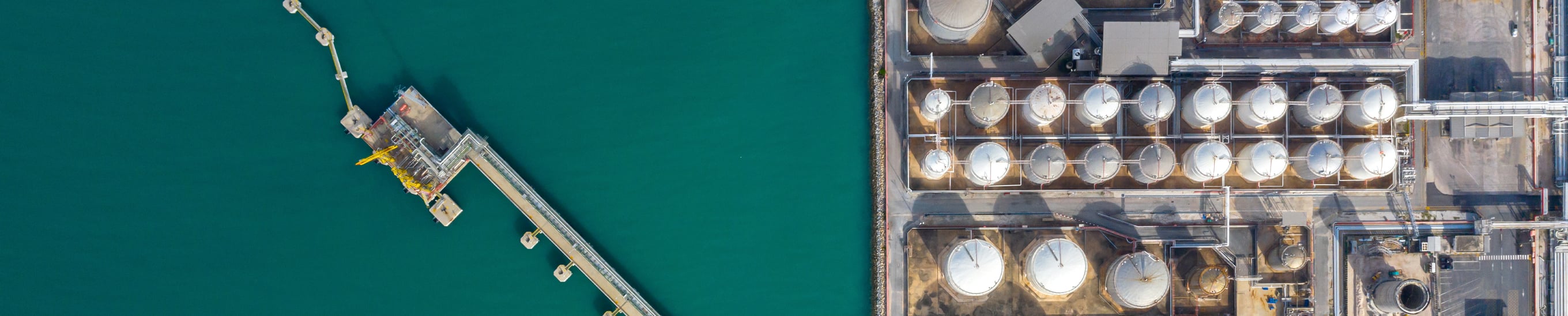 Aerial view of coastal energy infrastructure with storage tanks and marine terminal, reflecting power and utilities themes in Infrastructure Quarterly Q1 2026