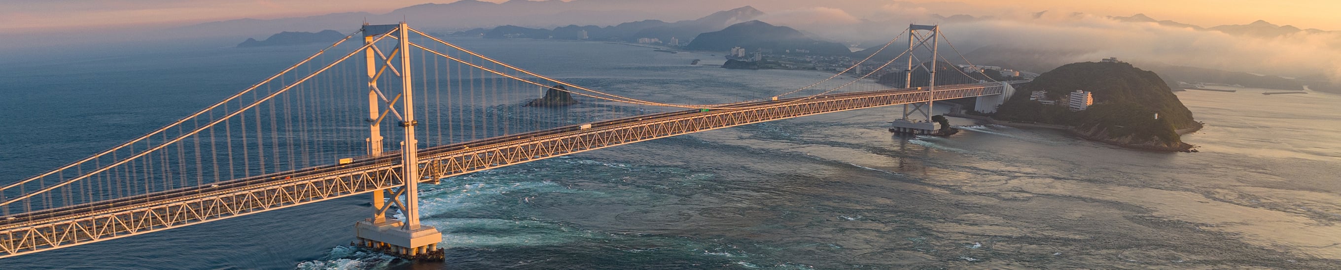 Aerial view of a major bridge spanning open water, symbolizing global trade flows and supply chain disruption in the Q2 2026 Macro House View.