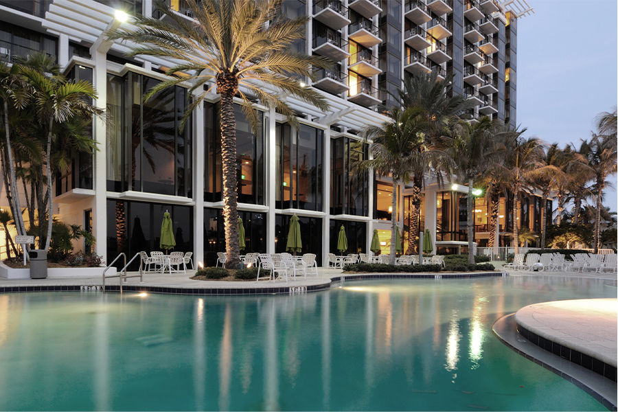 Luxury hotel with a pool and palm trees at dusk.