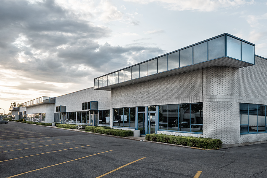 Modern office building with large windows and a parking lot.