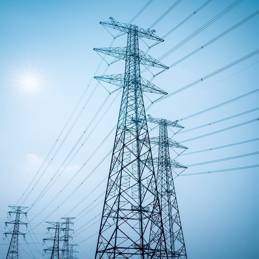 High-voltage power lines and transmission towers under a clear blue sky