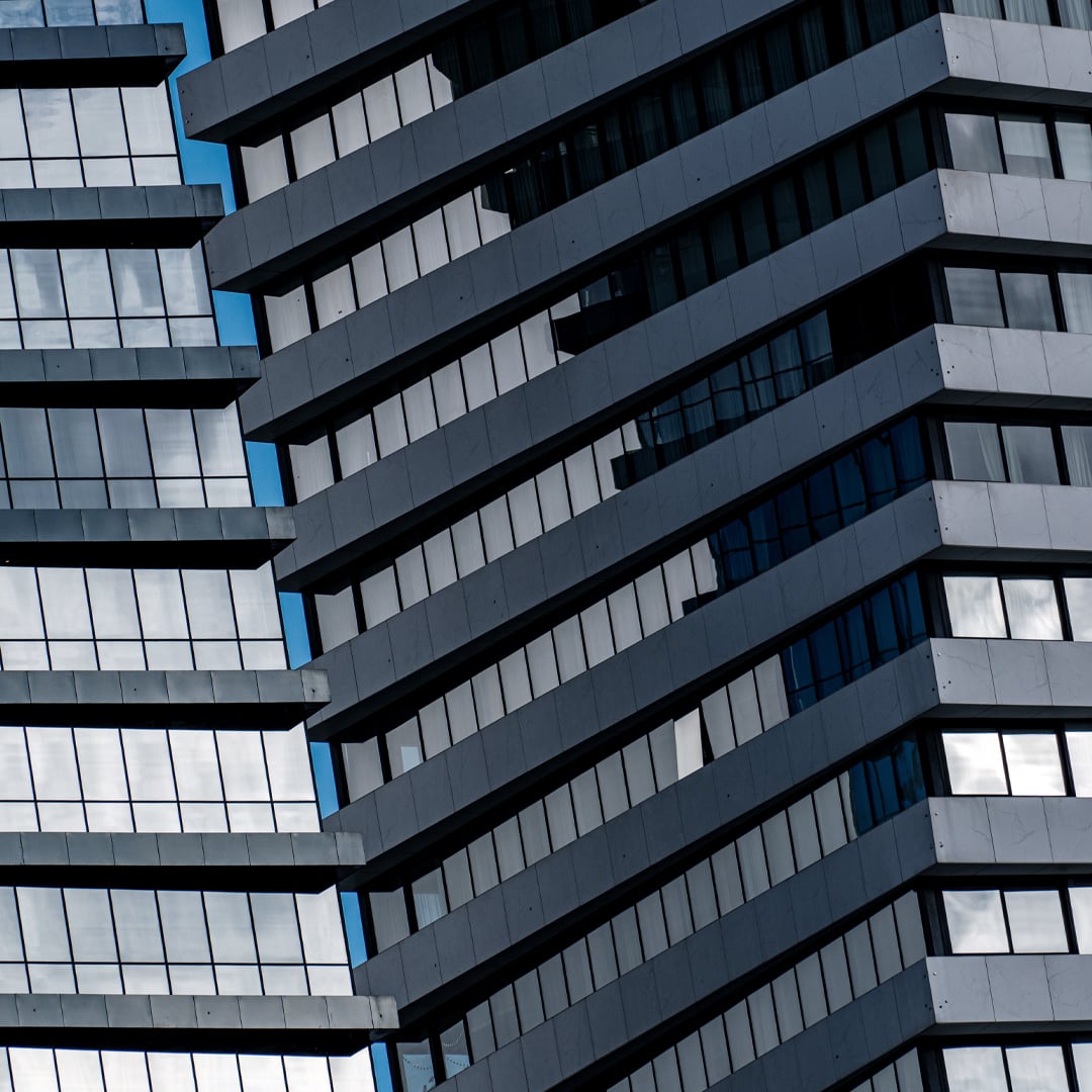Close-up view of modern high-rise building facade with glass windows and angled metal panels