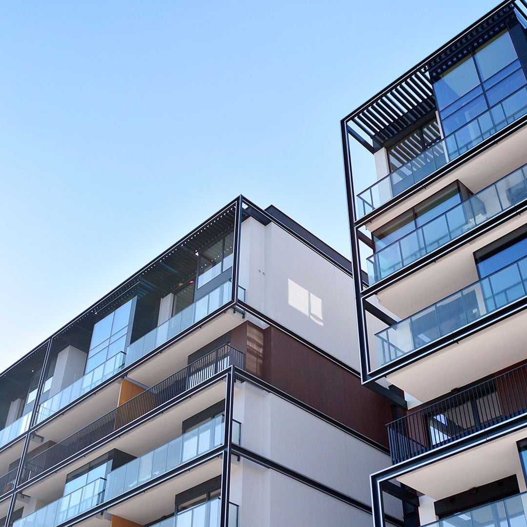 Modern apartment buildings with glass balconies under a clear blue sky