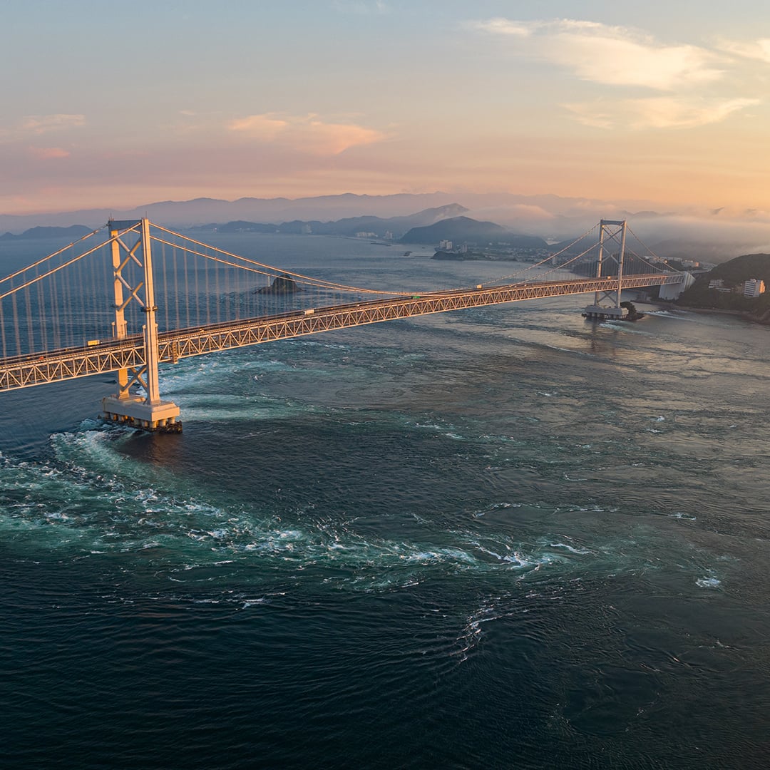 Aerial view of a major bridge spanning open water, symbolizing global trade flows and supply chain disruption in the Q2 2026 Macro House View.