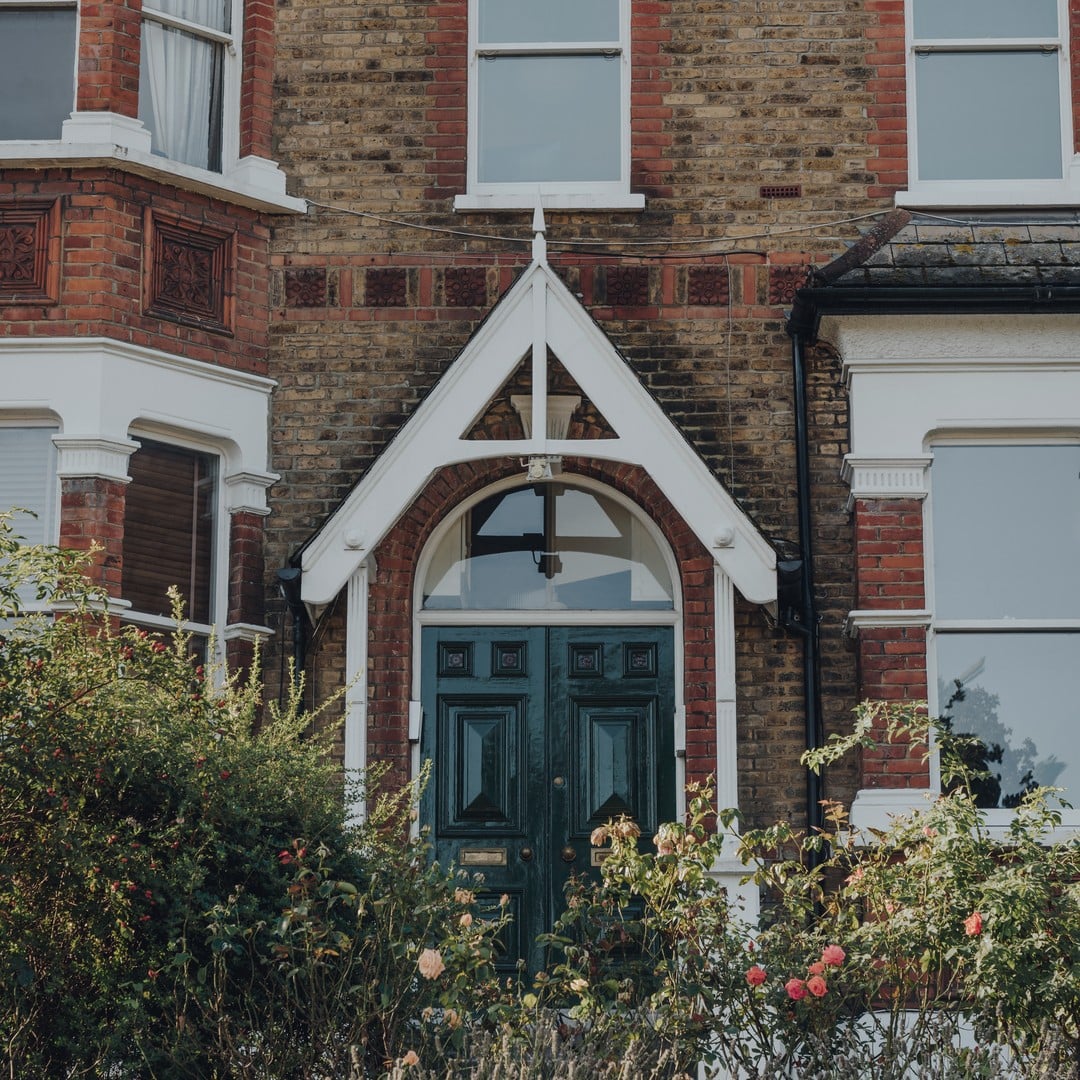 Front door and brick facade of a Victorian terraced house in London with a garden, representing U.K. single-family housing