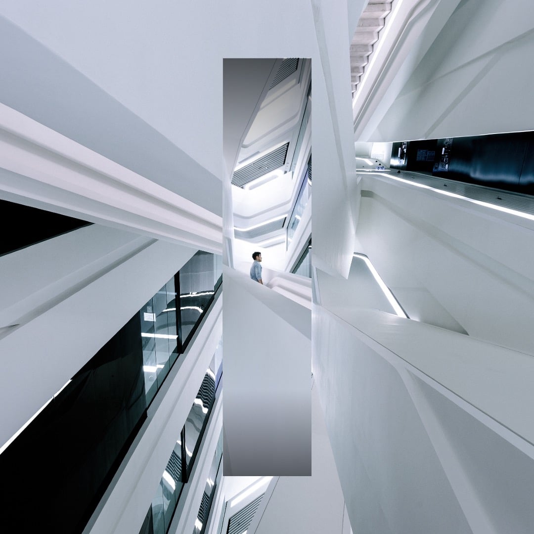 Abstract modern white architectural atrium with geometric lines and a person walking through a contemporary interior space.