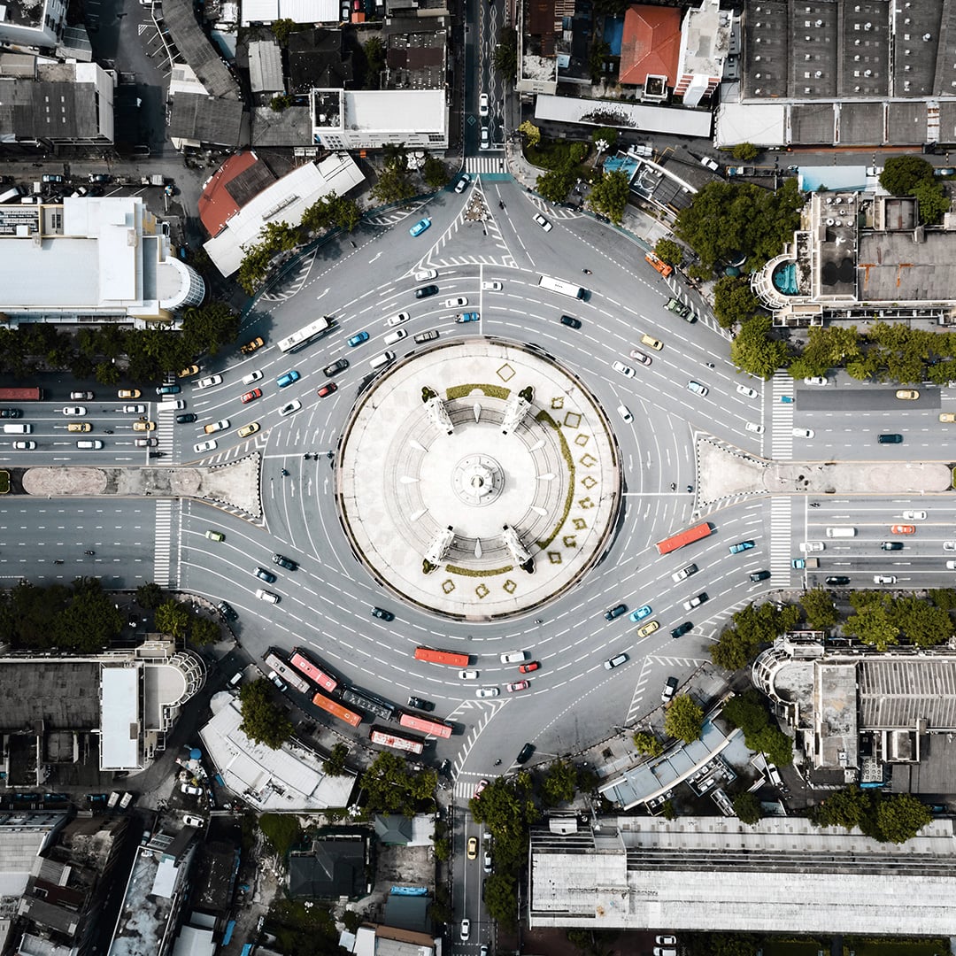 Aerial view of a busy city roundabout with cars and buses navigating multiple lanes.