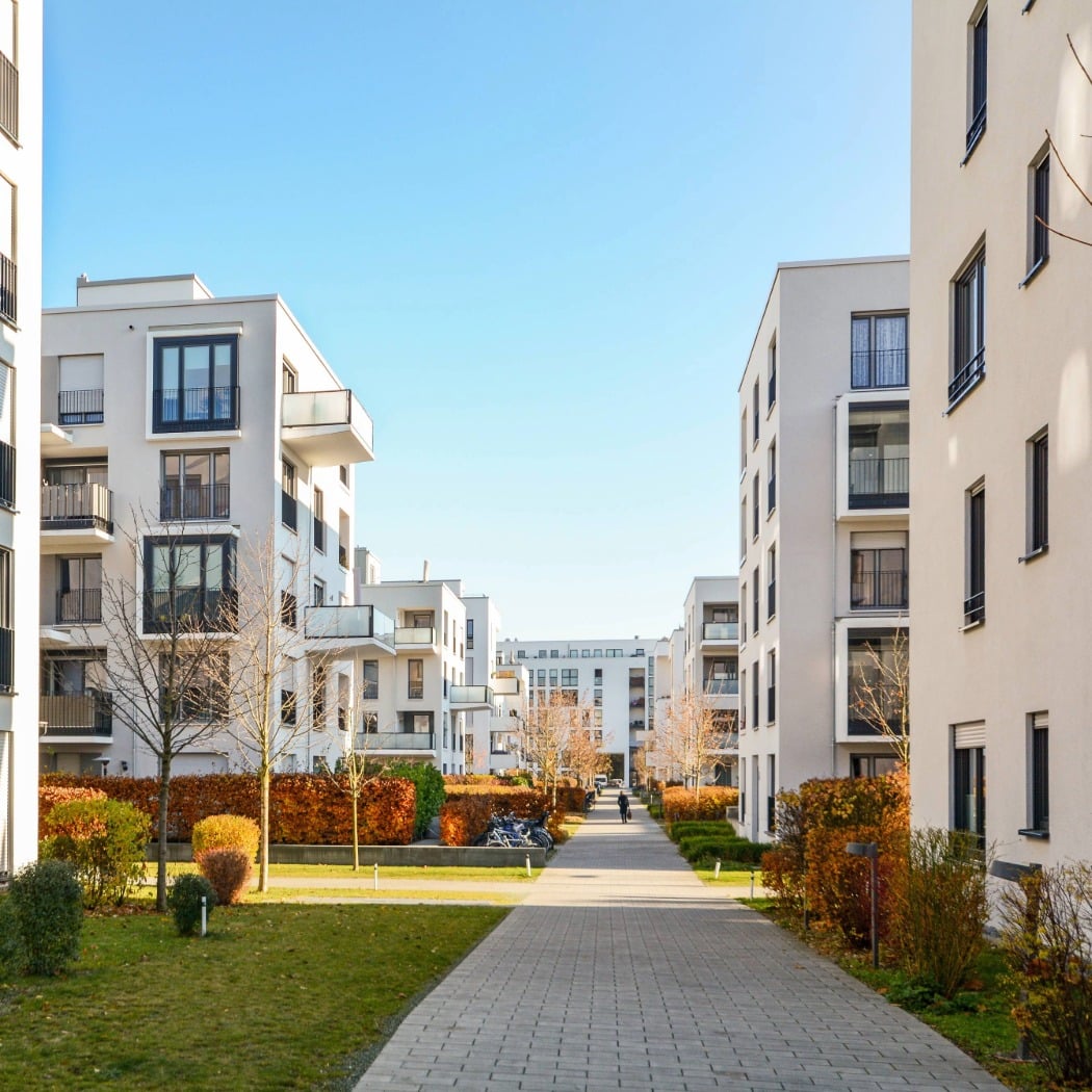 Modern multi-family apartment buildings with landscaped walkways and green spaces in a residential community.