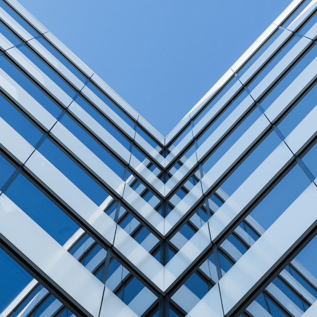 Symmetrical view of a modern glass office building reflecting the sky