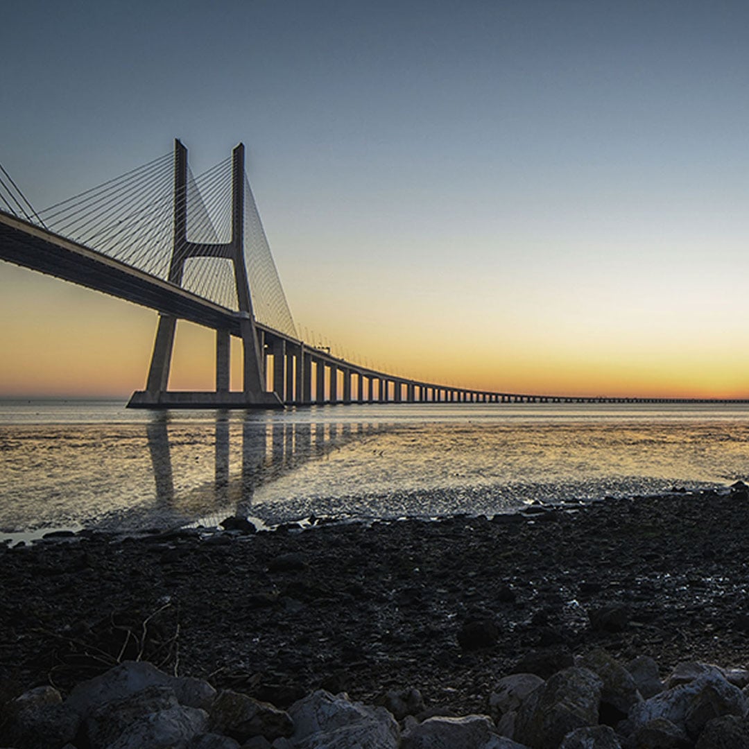 Cable-stayed bridge stretching across the water at sunset, representing global infrastructure