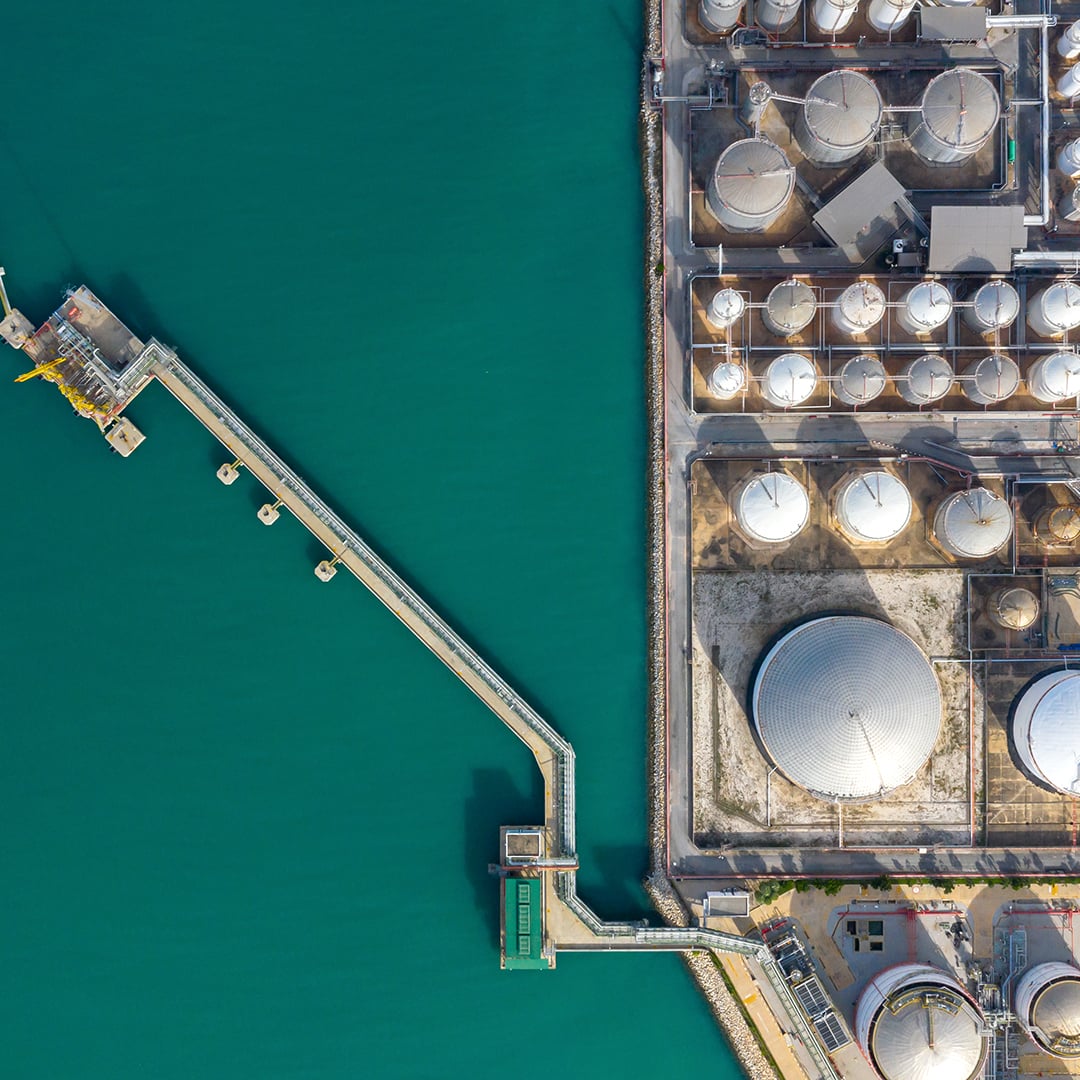 Aerial view of coastal energy infrastructure with storage tanks and marine terminal, reflecting power and utilities themes in Infrastructure Quarterly Q1 2026