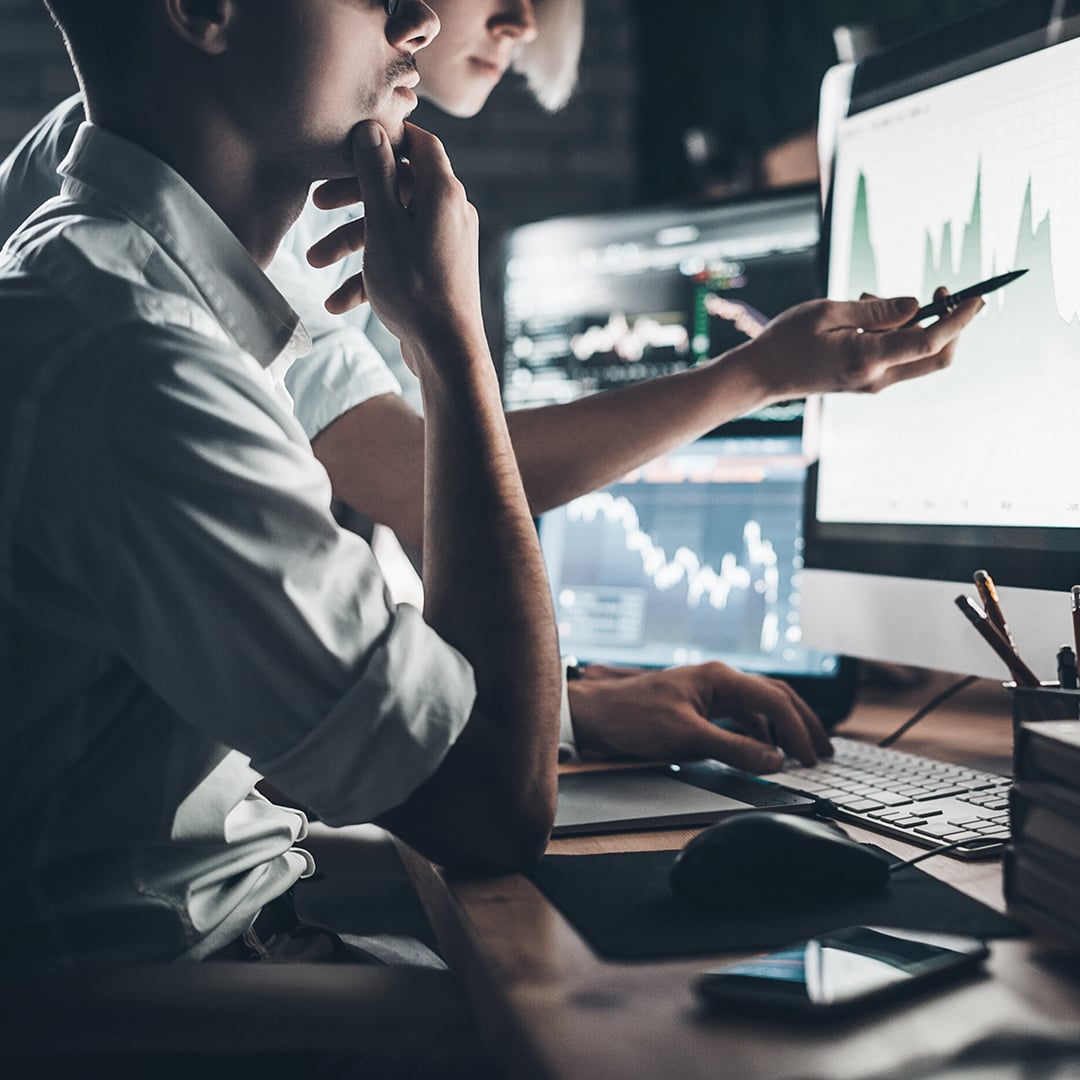 Marketing and data analytics professionals reviewing performance charts and graphs on computer screens
