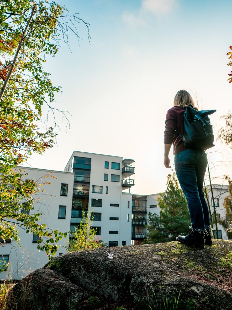 A person standing on a rock looking at a building
