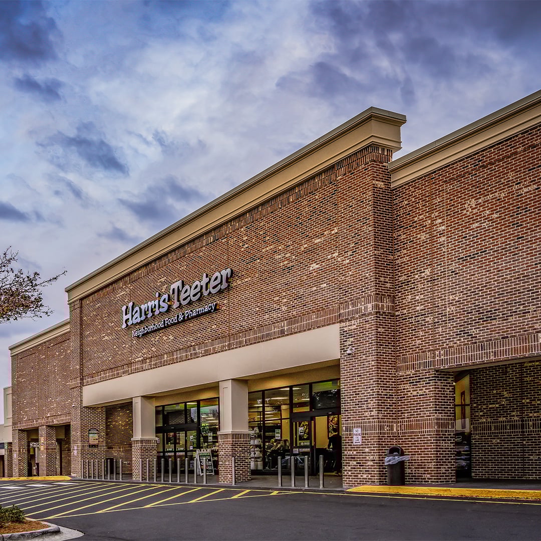 Exterior of a Harris Teeter grocery-anchored retail center with brick facade and surface parking lot