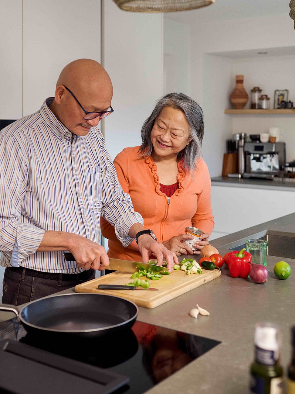 Older adults preparing fresh food together in a modern kitchen, reflecting independent living in sustainable and affordable senior housing in the Netherlands.
