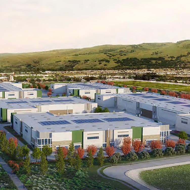 Aerial view of Cochrane Technology Center featuring multiple white and green buildings with rooftop solar panels, surrounded by landscaped greenery and hills in the background.