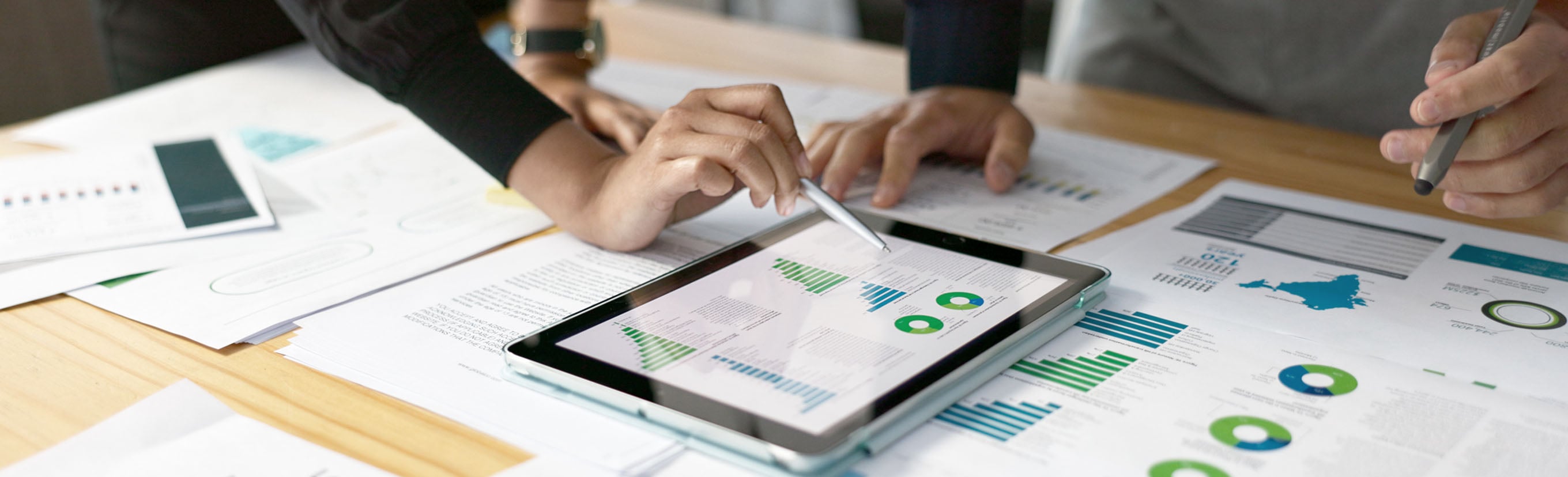 Colleagues comparing data on an iPad and printouts