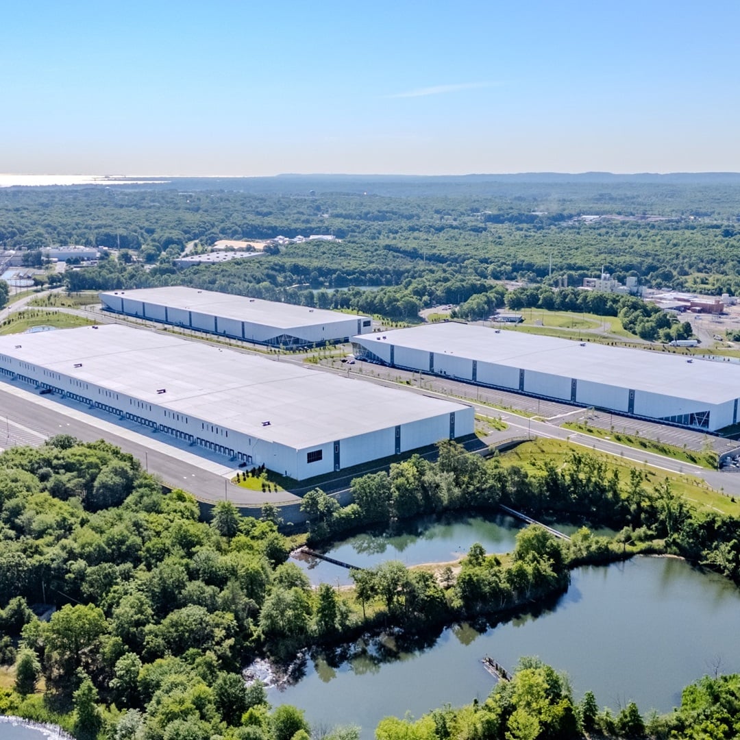 Aerial view of Arsenal Trade Center featuring large industrial warehouses surrounded by greenery and water.