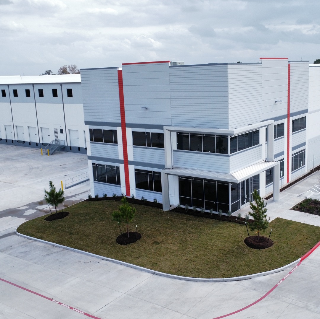 Aerial view of a modern industrial warehouse with office frontage, loading dock bays, and landscaped entry area.