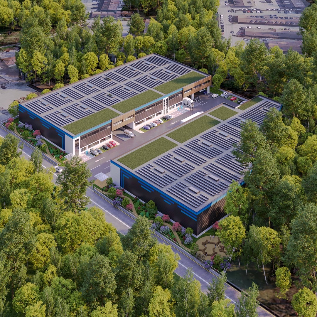 Aerial rendering of a modern industrial logistics facility with solar panels, green roofs, parking areas, and loading docks surrounded by trees.
