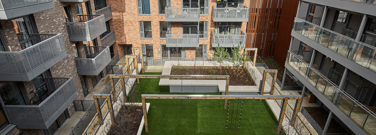 Modern apartment courtyard with balconies, green space, and wooden structures.
