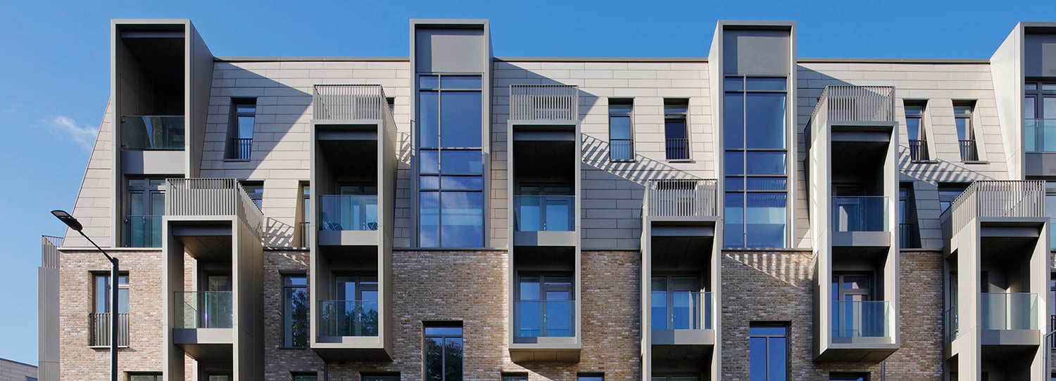 Modern building facade with protruding balconies and large windows against a clear blue sky.
