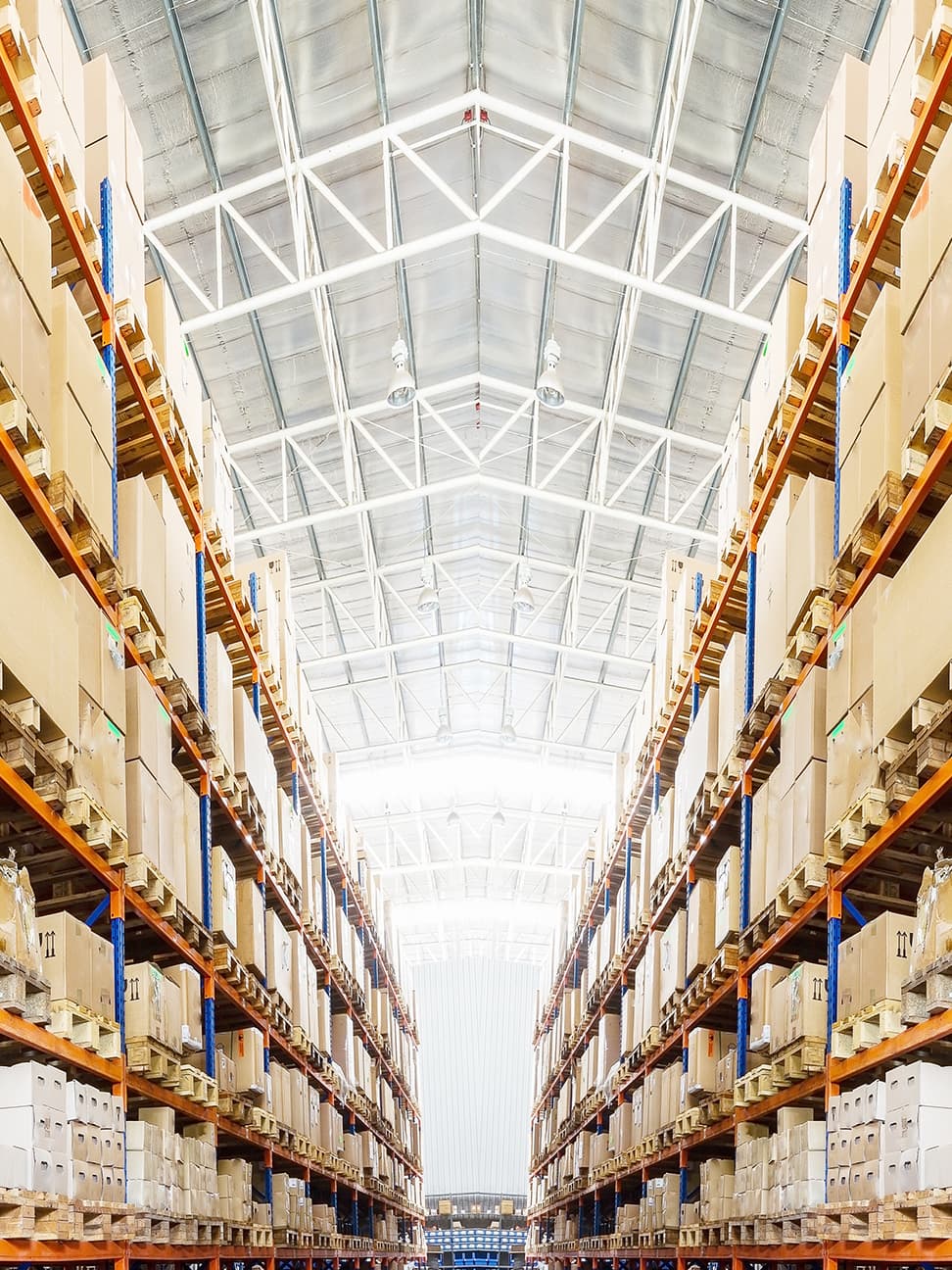 Expansive aisle in a modern Toronto industrial warehouse, flanked by tall pallet racking shelves loaded with cardboard boxes, illustrating efficient inventory storage and logistics.