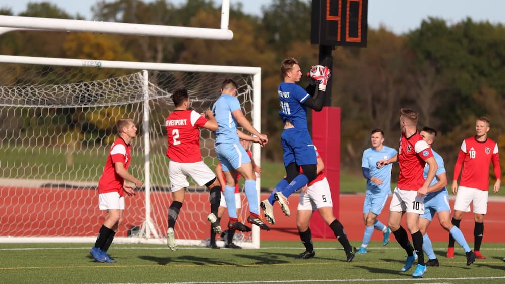Au centre, Josh Doupe attrape un ballon de soccer en plein vol.