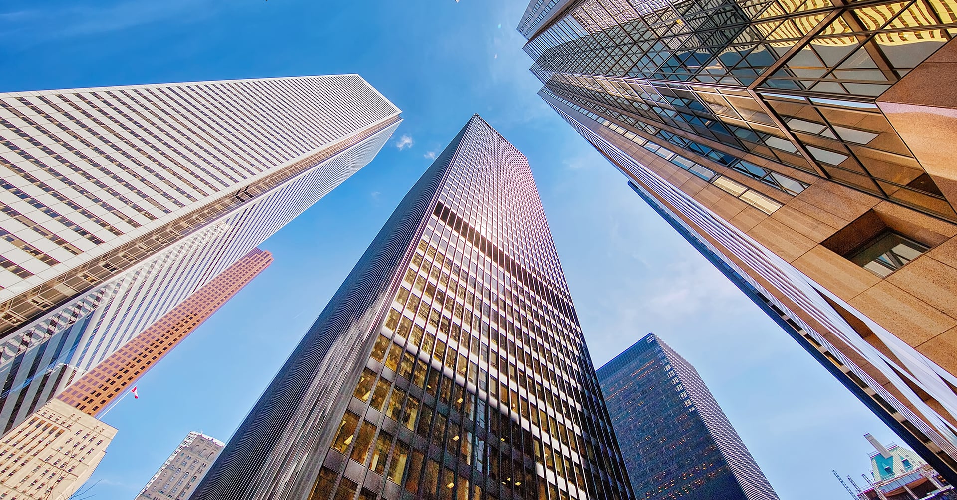 Upward view of downtown office skyscrapers against a blue sky