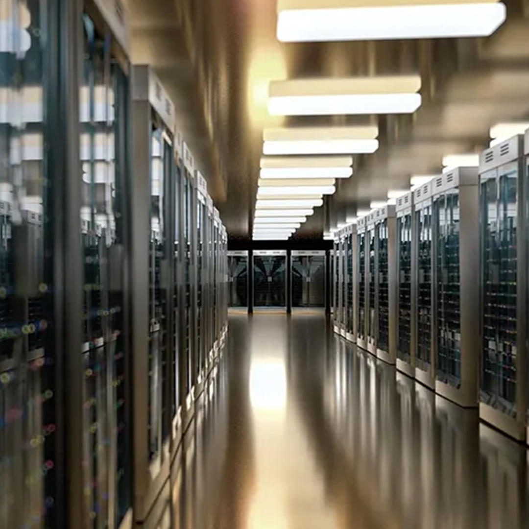 A long, brightly lit corridor in a data centre, with rows of server racks extending into the distance on both sides.