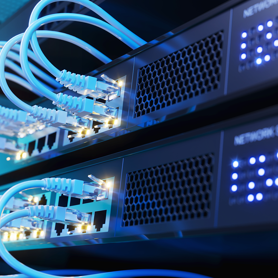 A close-up of multiple light blue ethernet cables plugged into dark network switches, with glowing yellow and blue indicator lights, hinting at data flow.