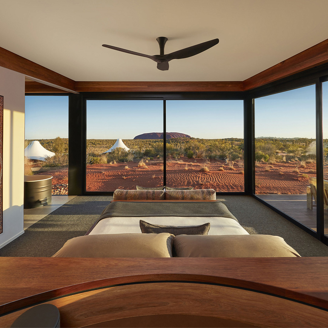 A stunning bedroom with floor-to-ceiling windows showcasing Uluru in the Australian outback.