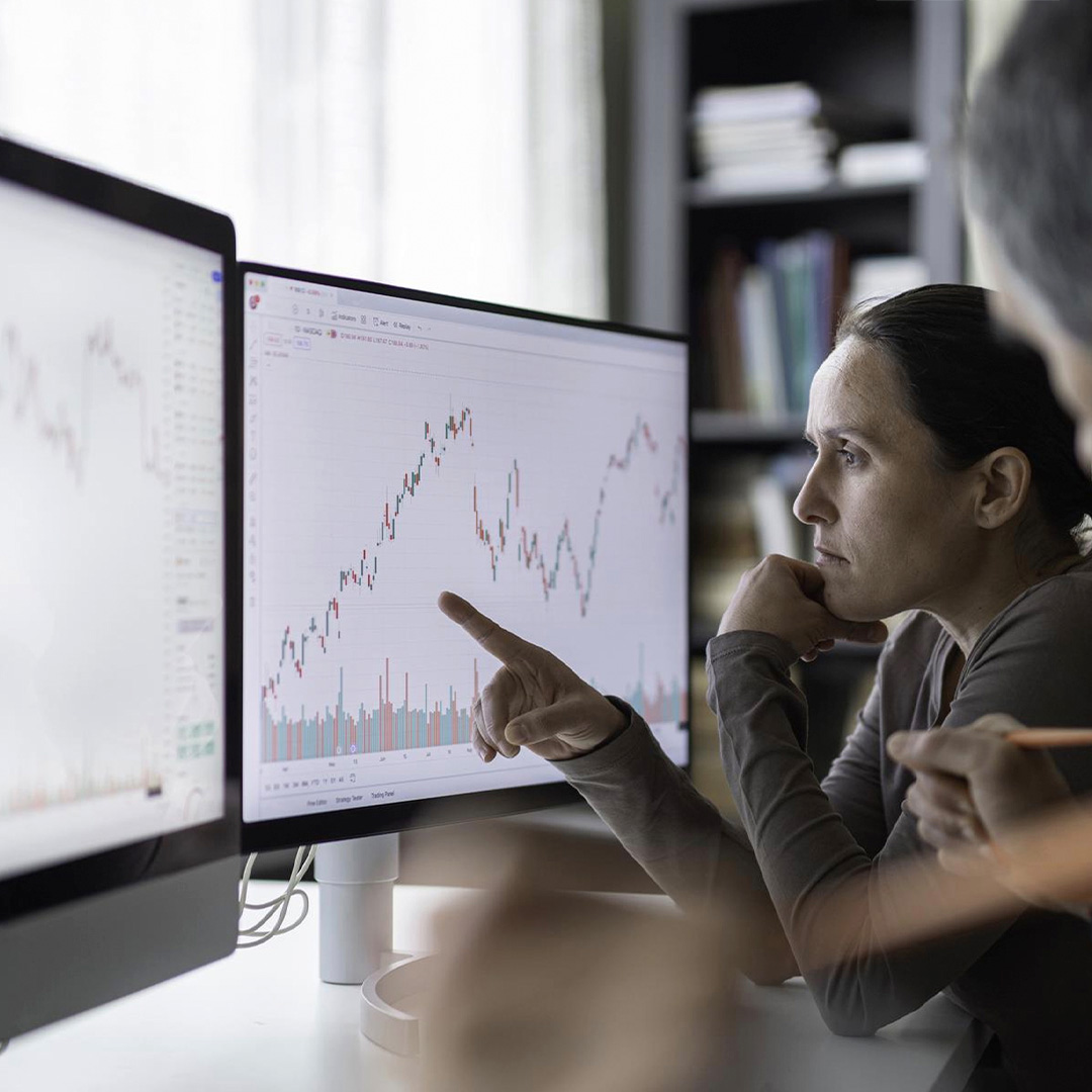 Two people analyse a stock market graph on a computer screen.
