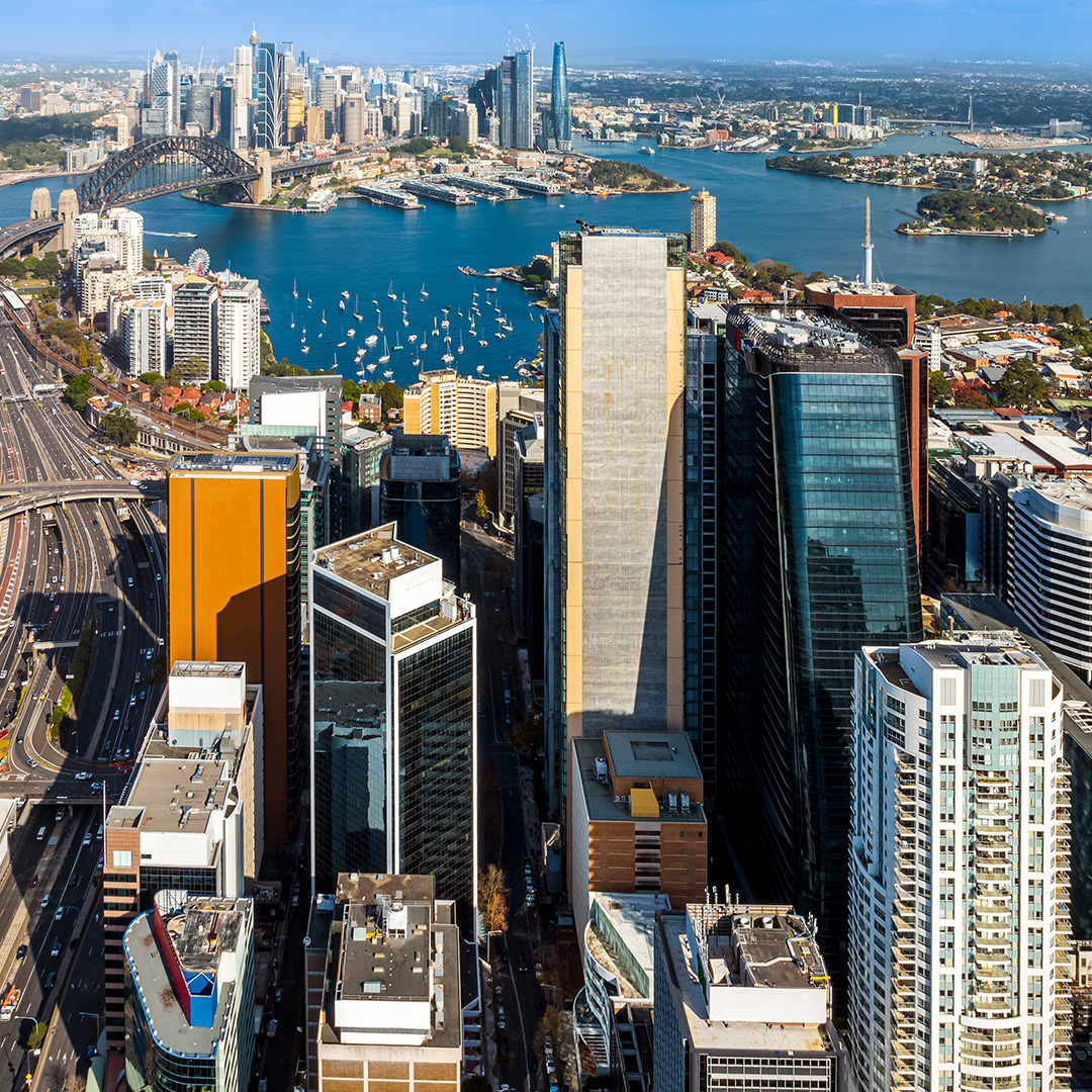 The image shows an aerial photo of Sydney's city skyline and harbour.