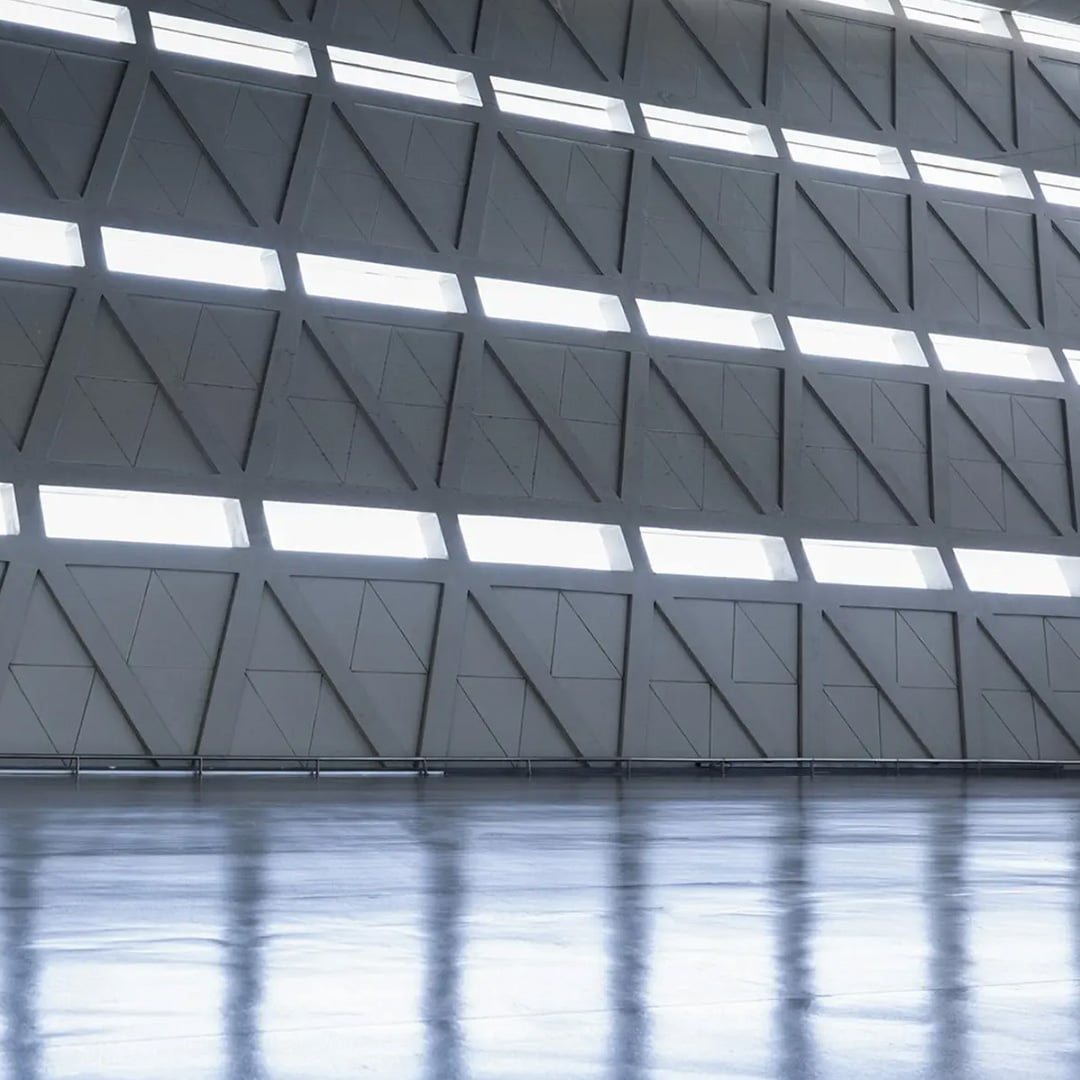 Abstract image of a modern building's interior with a geometric wall and reflective floor.