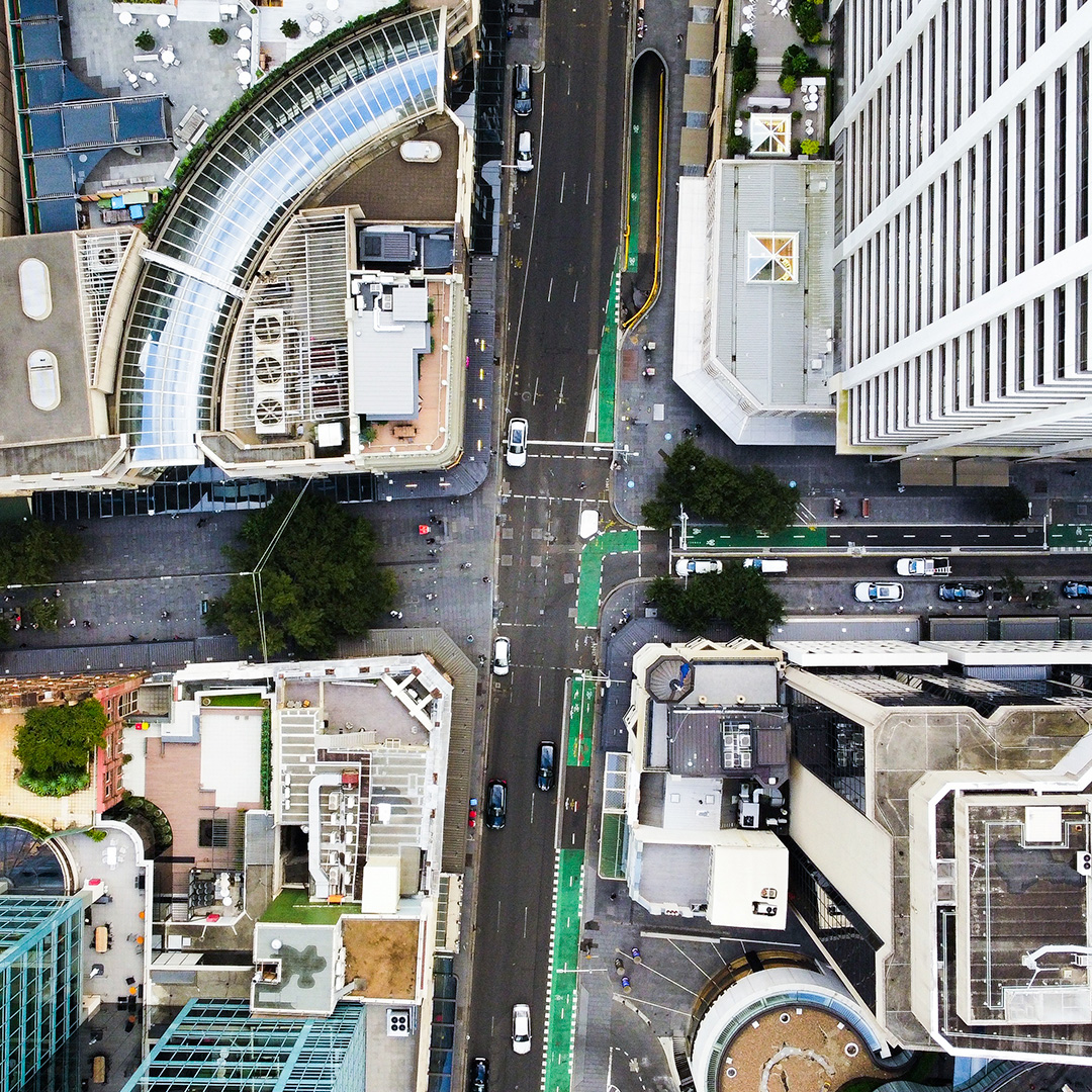 Aerial view of a city intersection showing buildings, roads, and a few cars.
