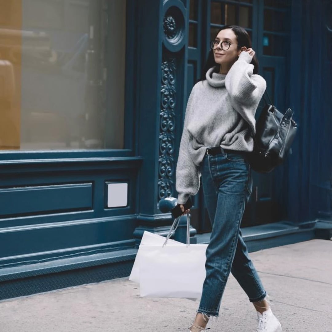 A woman walks down the street carrying shopping bags and a backpack.
