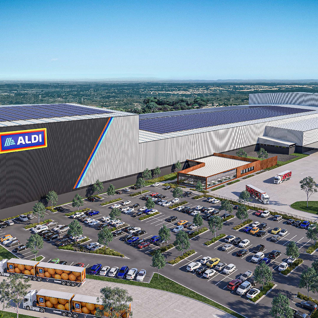 Aerial view of an Aldi distribution centre with a large car park, branded trucks, and rooftop solar panels.