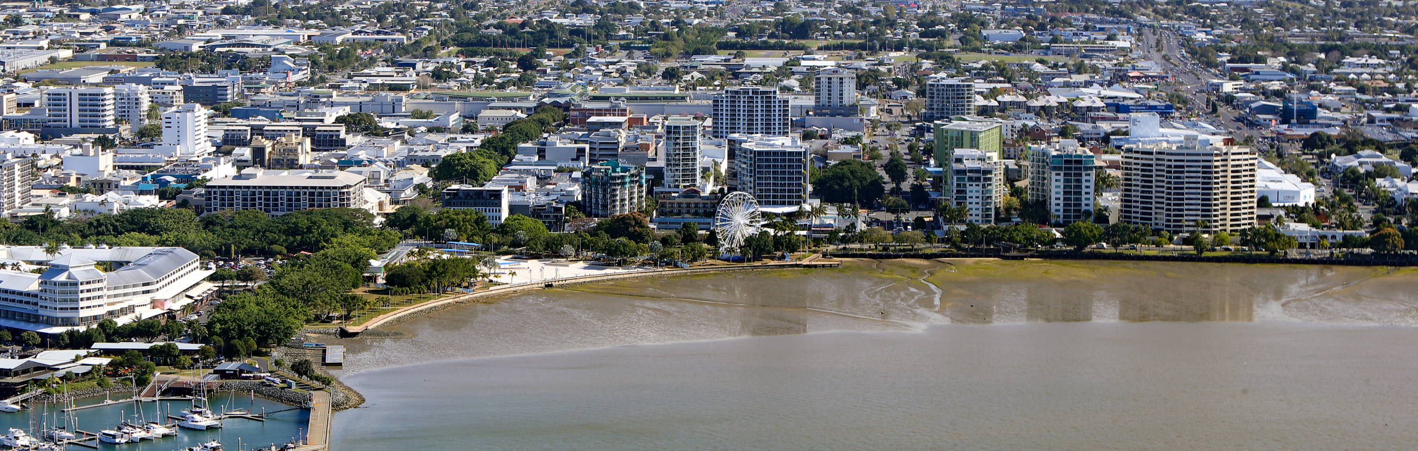 Aerial view of Cairns city centre, showcasing its waterfront, high-rise buildings, and the Cairns Esplanade.