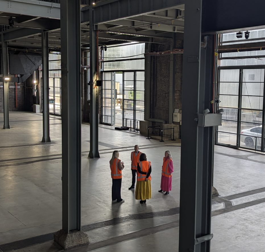 A group of people in high-visibility vests stand in the vast, industrial interior of the revitalised White Bay Power Station in Sydney, Australia.