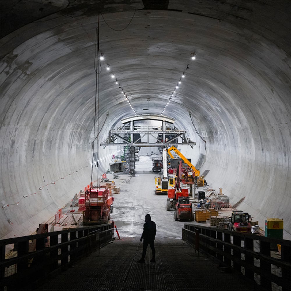 A person surveys the interior of a large, newly completed tunnel, highlighting the scope of Australian infrastructure investment. 