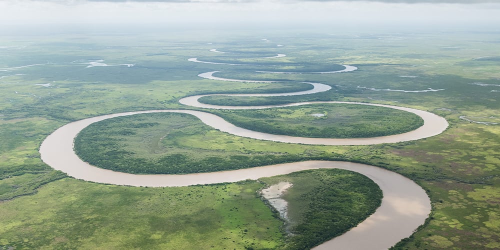 Aerial view of a meandering river showcasing the continuous flow and adaptability needed for navigating market challenges in the property sector. 