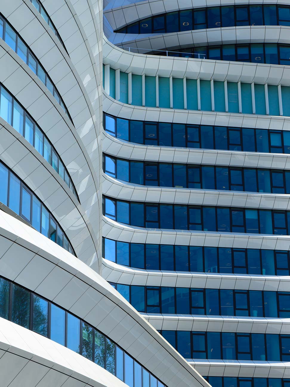 Kantoorgebouw met gebogen witte gevel en blauwe glazen ramen, zichtbaar in een strak architectonisch ontwerp voor commercieel vastgoed en kantoorruimte.