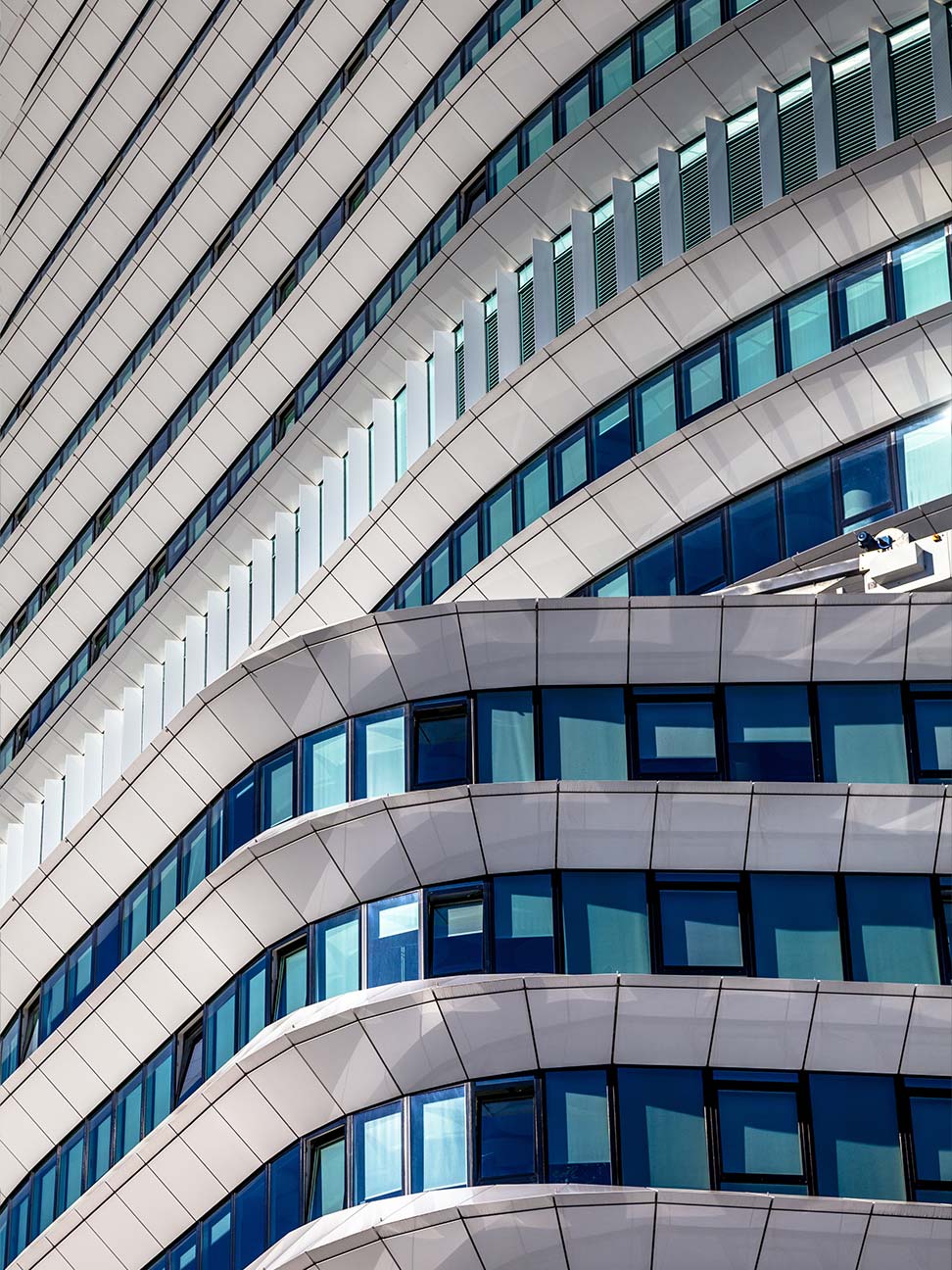 Kantoorgebouw met gebogen witte gevel, blauwe glazen ramen en verticale lamellen, zichtbaar in een opvallend ontwerp voor commercieel vastgoed en kantoorruimte.