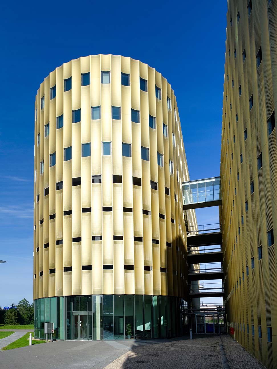 Kantoorgebouw in Zwolle met goudkleurige gevel, glazen entree en verbindende loopbruggen tussen bouwdelen, geschikt voor kantoorruimte en zakelijke huisvesting.