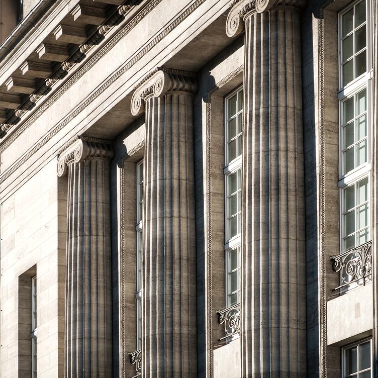 Detail of a neoclassical building with large stone columns and ornate architectural elements.