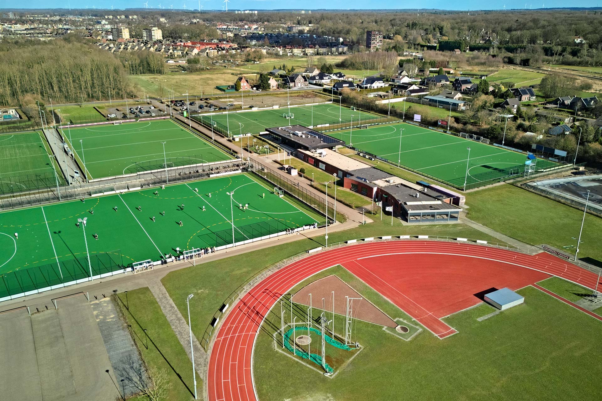 Luchtfoto van een multifunctioneel sport- en voorzieningencomplex omringd door bebouwing en open gebied, illustratief voor ruimtelijke planning en gebiedsontwikkeling.