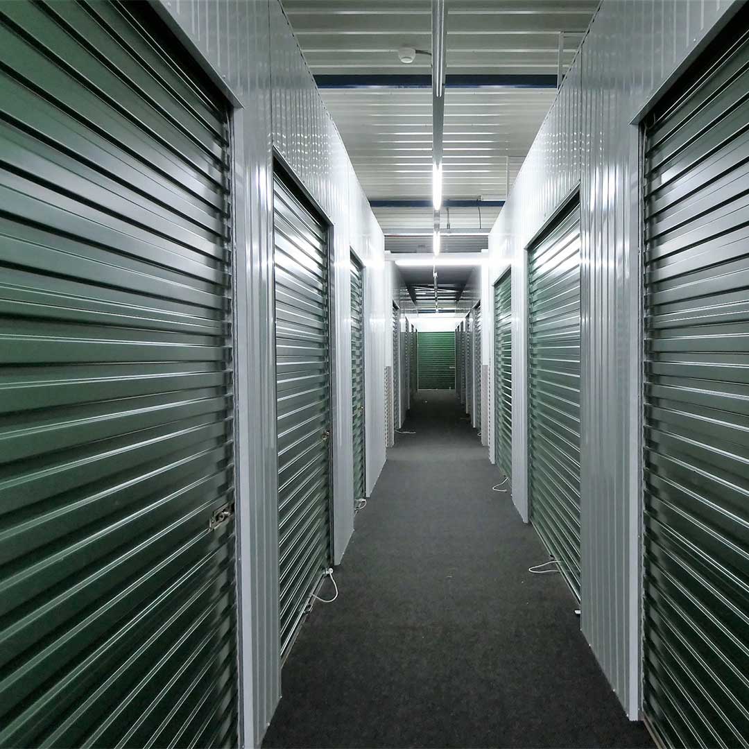 Moderne self-storage gang met groene roldeuren en Ledverlichting in een professionele opslagfaciliteit