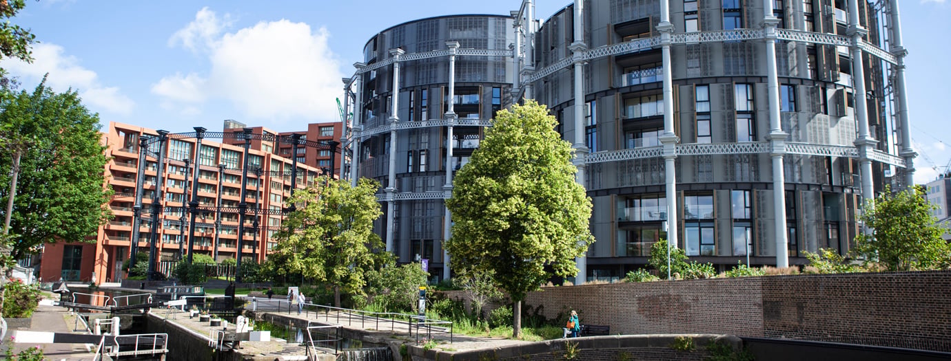 Gasholders residential buildings at King’s Cross beside Regent’s Canal, with trees and a canal lock in the foreground.
